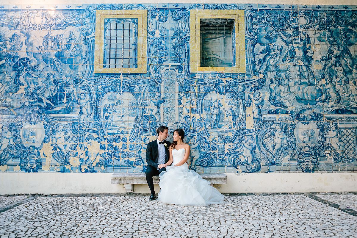 couple sitting on their destination wedding against an ancient art colored wall in portugal