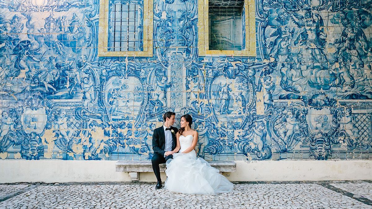 couple sitting on their destination wedding against an ancient art colored wall in portugal